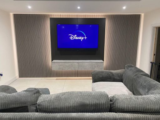 Modern living room with a large TV displaying the Disney logo and a grey sofa.