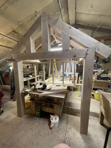 A wooden structure resembling a partially built cabin in a workshop.