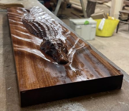 Wooden carving depicting a detailed crocodile design on a polished surface.